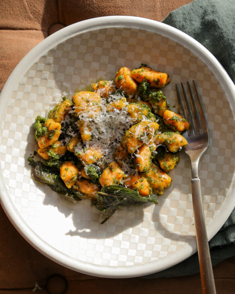 a plate of homemade sweet potato gnocchi with sage pesto and parmesan on top