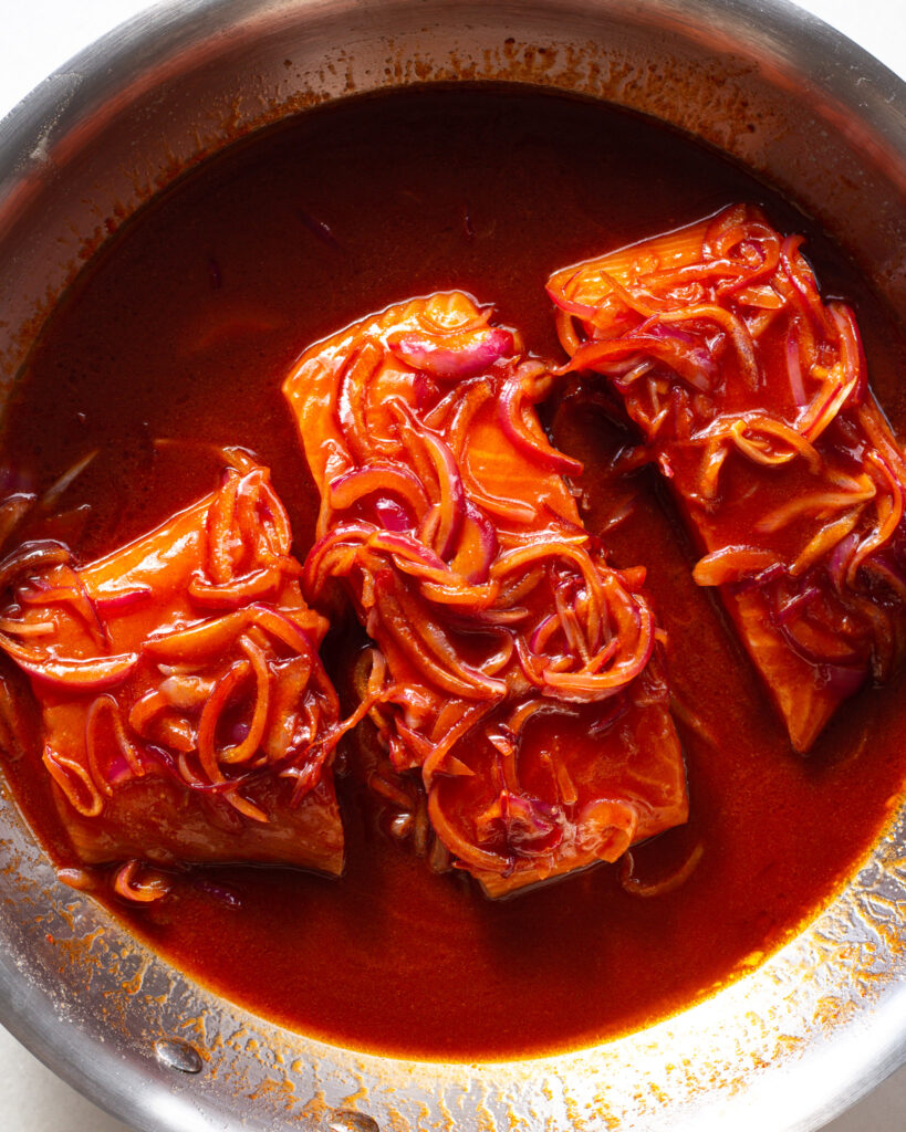 Salmon, sauce and onions in pan
