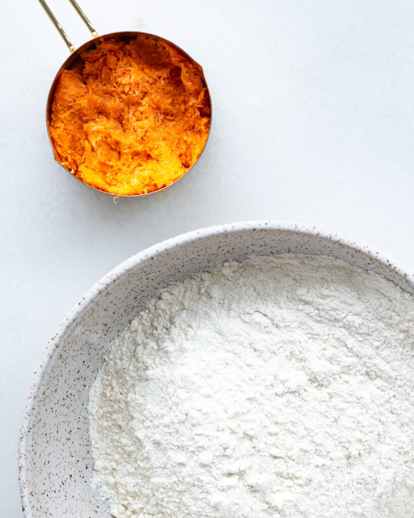 grated carrot in a measuring cup and biscuit dry ingredients in a bowl