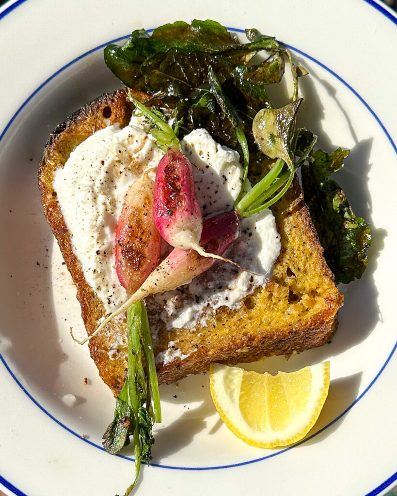 Savory french toast with breakfast radishes serves on a plate with a wedge of lemon